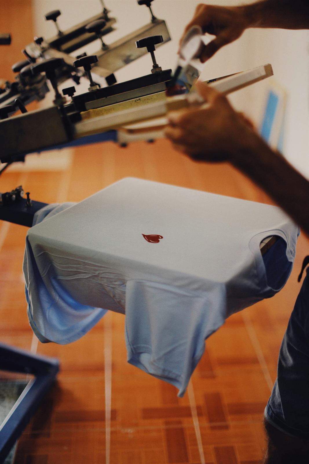 Team member printing a shirt on a screen printing station